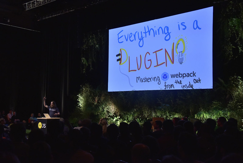 Sean Larkin in front of the giant screen showing an hand drawn picture with the talk title